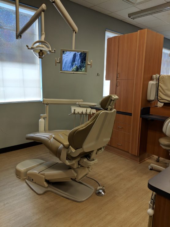 Interior of dental exam room at Cole White Dental with dental chair and TV screen